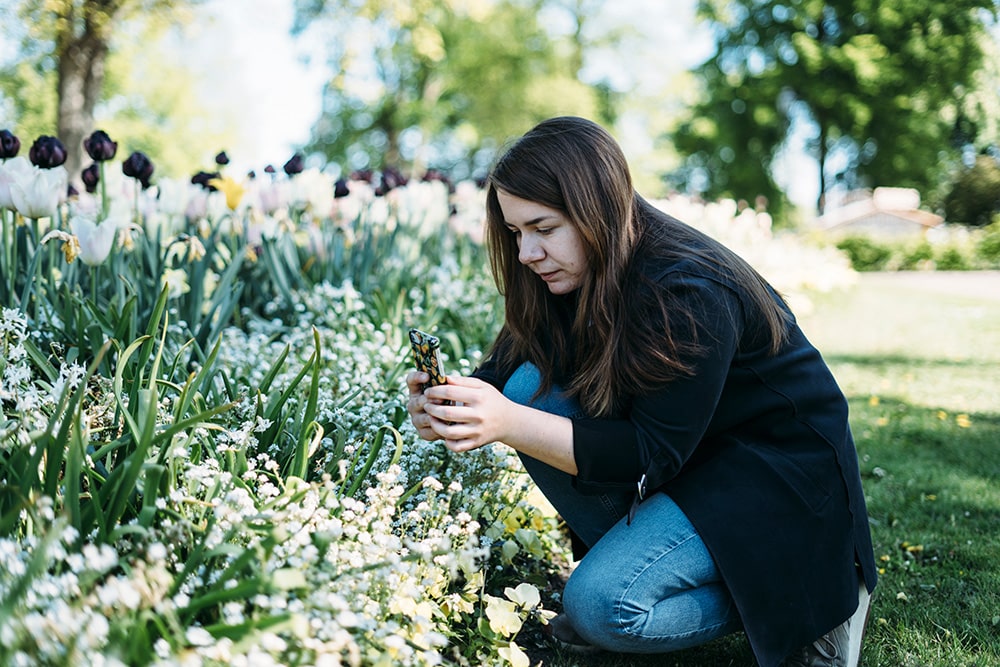Angelica fotar blommor på marken med sin mobil