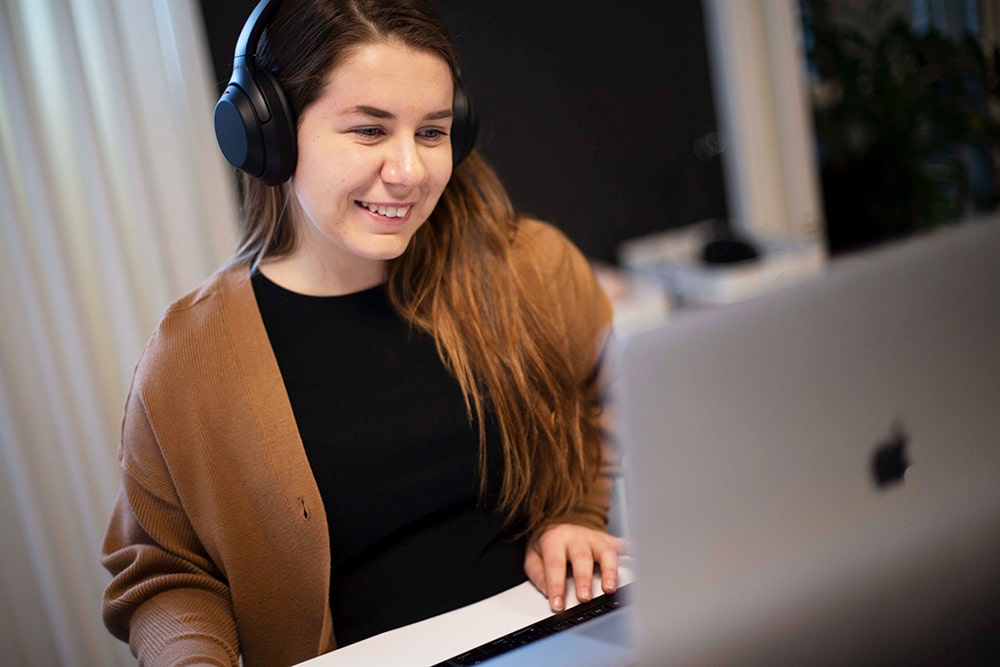 Angelica sår vid en datorskärm och redigerar video med hörlurar på sig