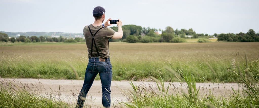 En man tar landskapsfoto med sin mobil.