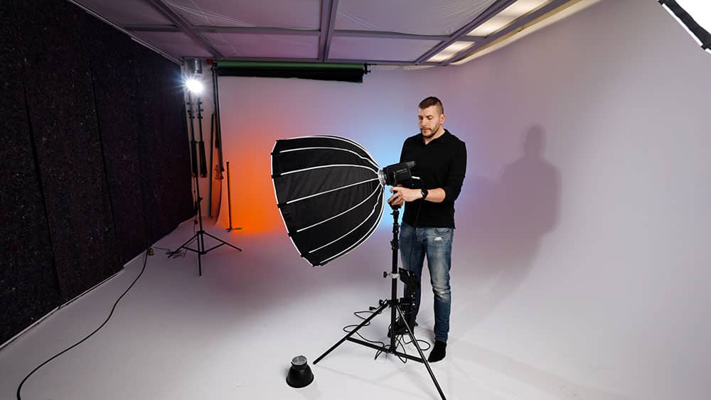 Person står i en videostudio och fixar med ljuset