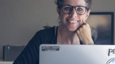 Leende kvinna framför mac-dator.