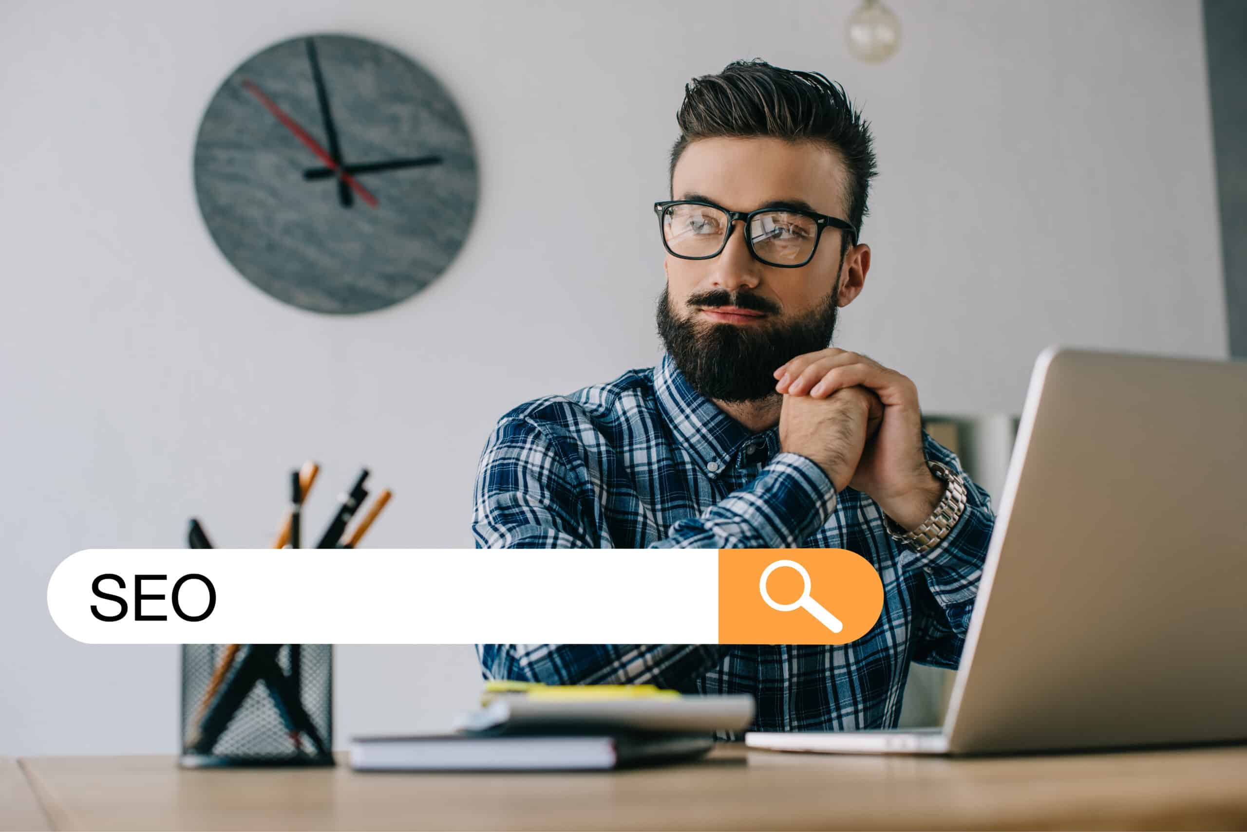 omtänksam ung utvecklare tittar bort medan han sitter på arbetsplatsen med laptop och SEO-sökning
