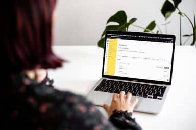 Kvinna fotograferad bakifrån som jobbar med datorn. På skärmen syns verktyget Mailchimp.