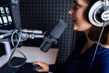 Person spelar in sin röst i ett ljudbås vid en mikrofon