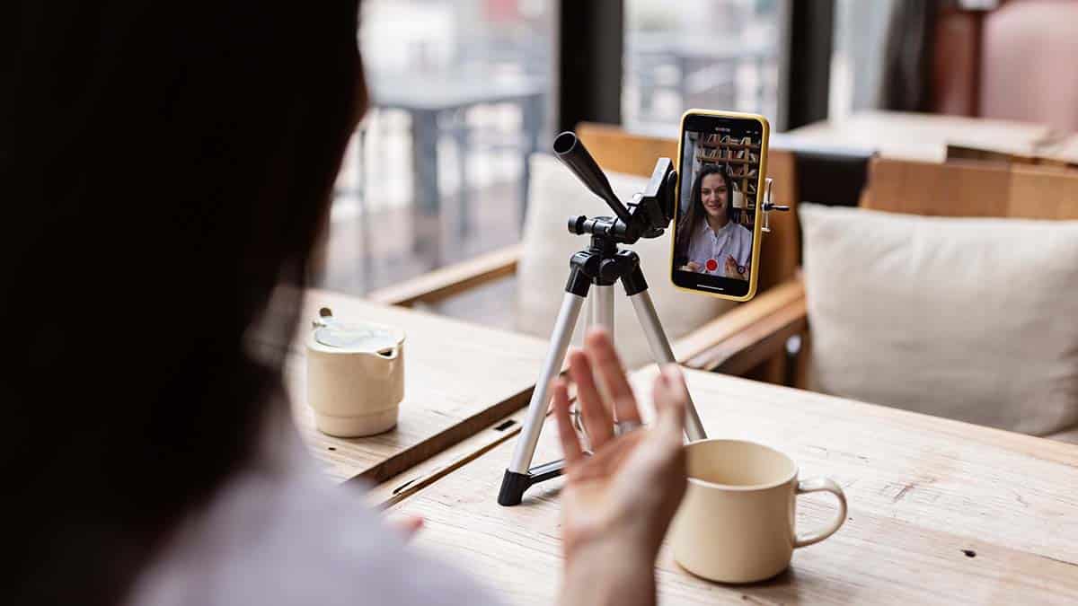 Kvinna som filmar en video med mobilen på ett stativ