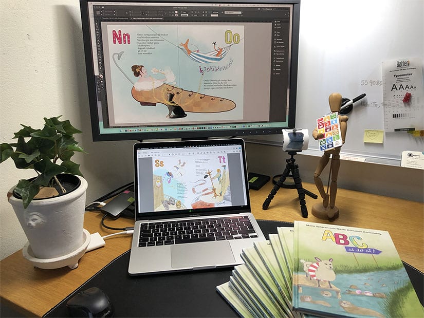 Skrivbord med skärmar där du ser illustrationer från boken