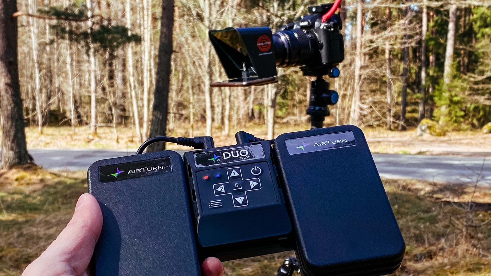 En pedal till en teleprompter med en kamera och en monterad teleprompter i bakgrunden