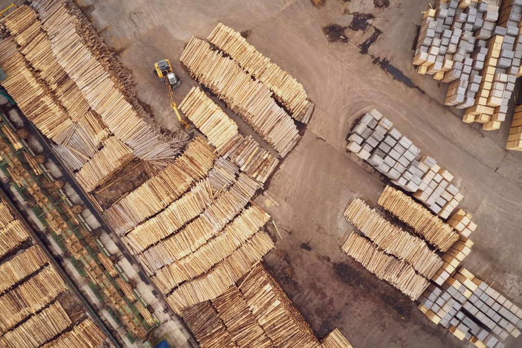 Bild tagen ovanifrån på staplar med strädstammar inom skogsindustrin.