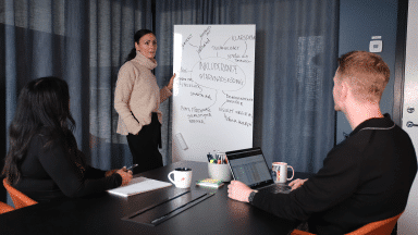 Tre personer diskuterar mångfald och inkludering i marknadsföring vid en whiteboard.