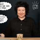 Nöjd kvinna sitter vid ett skrivbord med illustrerade distraktioner som notissymboler och pratbubblor som ignoreras runtom. I bakgrunden står en hylla med en växt, en klocka, en tavla, en lampa och på skrivbordet finns en kaffekopp och en laptop.