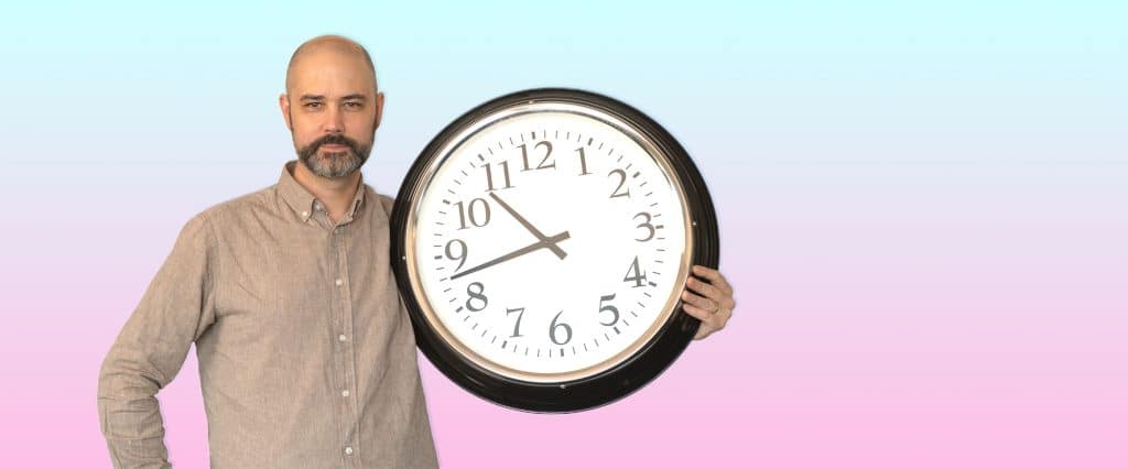 Fredrik Larsson, lärare i kursen Time management, tittar mot kameran och håller i en stor väggklocka.