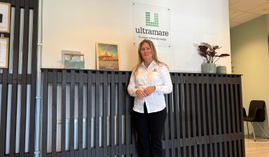 Erica Sirviö-Musta poserar framför Ultramares logotyp i deras lokaler i Trollhättan.