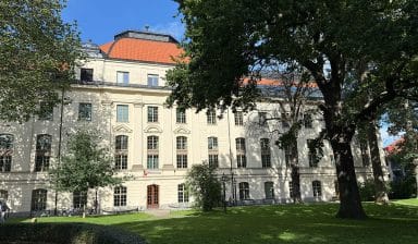 Folkuniversitetets lokaler i Stockholm från innergården, med pampiga träd, fint klippt gräs och grusgångar.