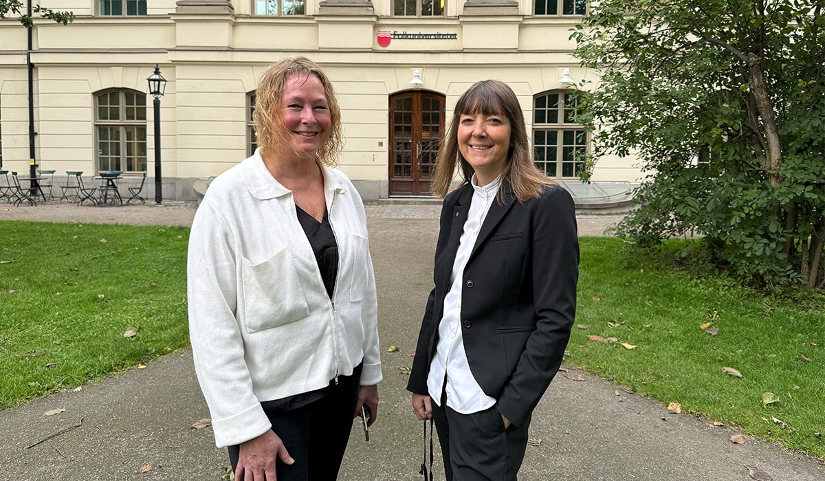Cecilia Leufstedt, till vänster, och Michaela Zankl, ler mot kameran framför Folkuniversitetets lokaler i centrala Stockholm.