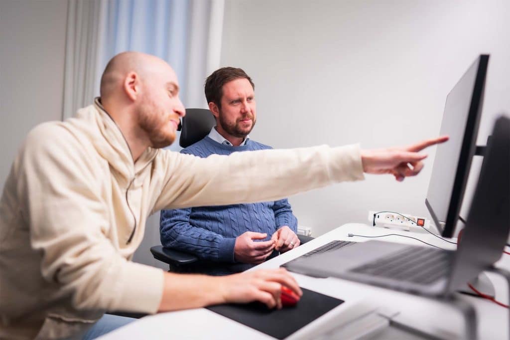 En medarbetare hjälper en annan medarbetare vid datorn.