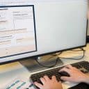 Närbild på en person som arbetar med kursens arbetsdokument för experimentplanering på en datorskärm. Dokumentet visar fält för att beskriva, motivera och planera ett experiment.