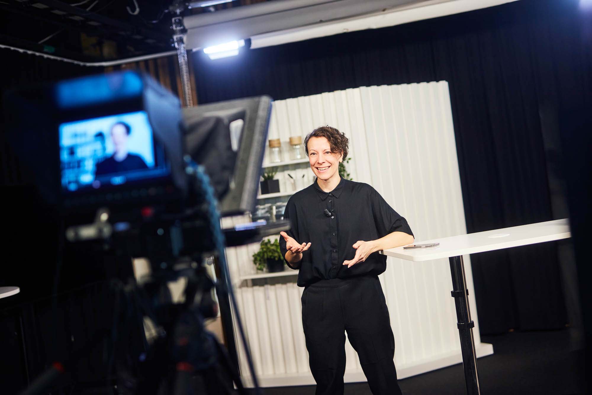 Josefina står i en videostudio med en studiokamera riktad mot sig som hon pratar in i.