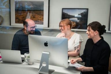 Tre medarbetare som samarbetar framför en dator