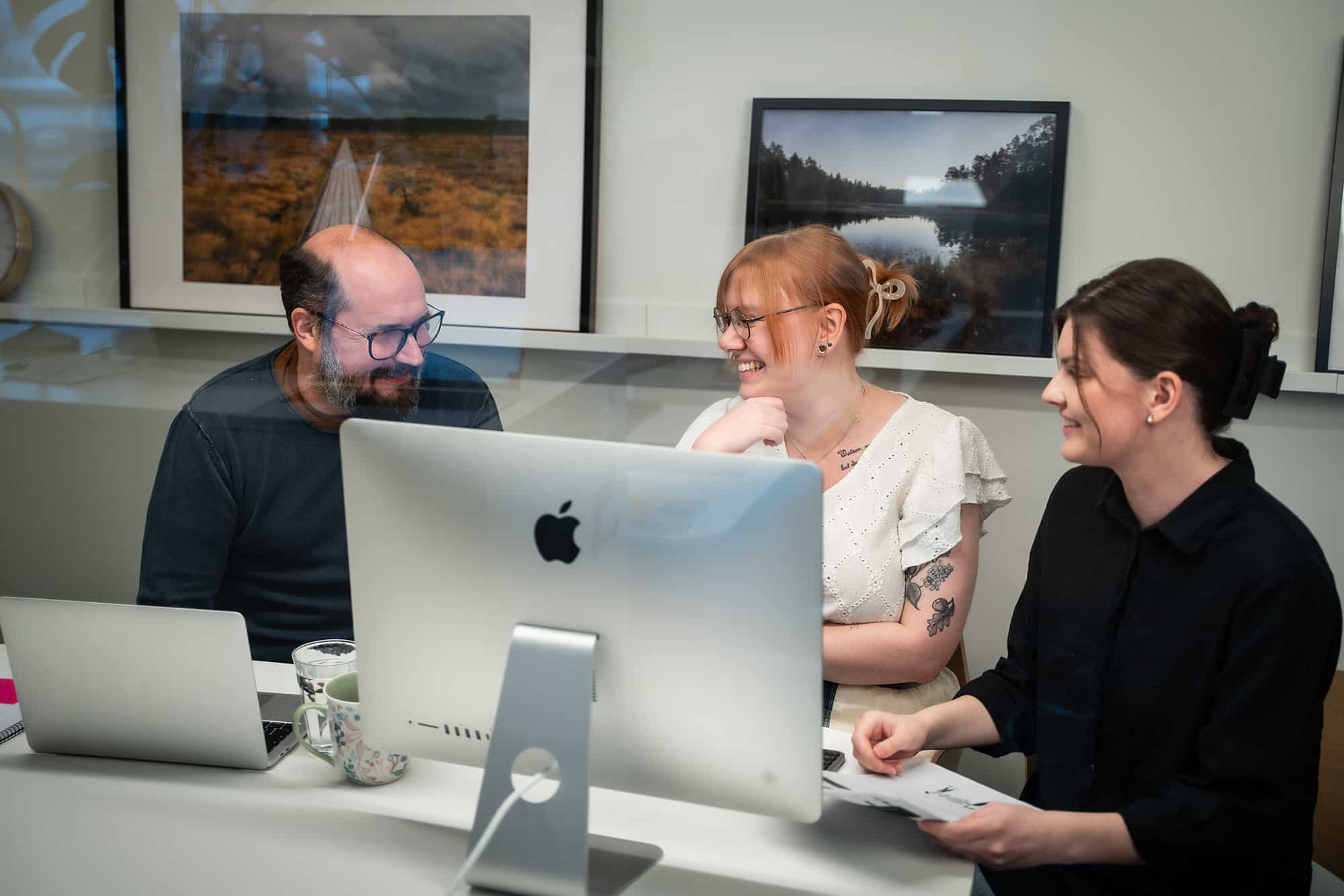 Tre medarbetare som samarbetar framför en dator
